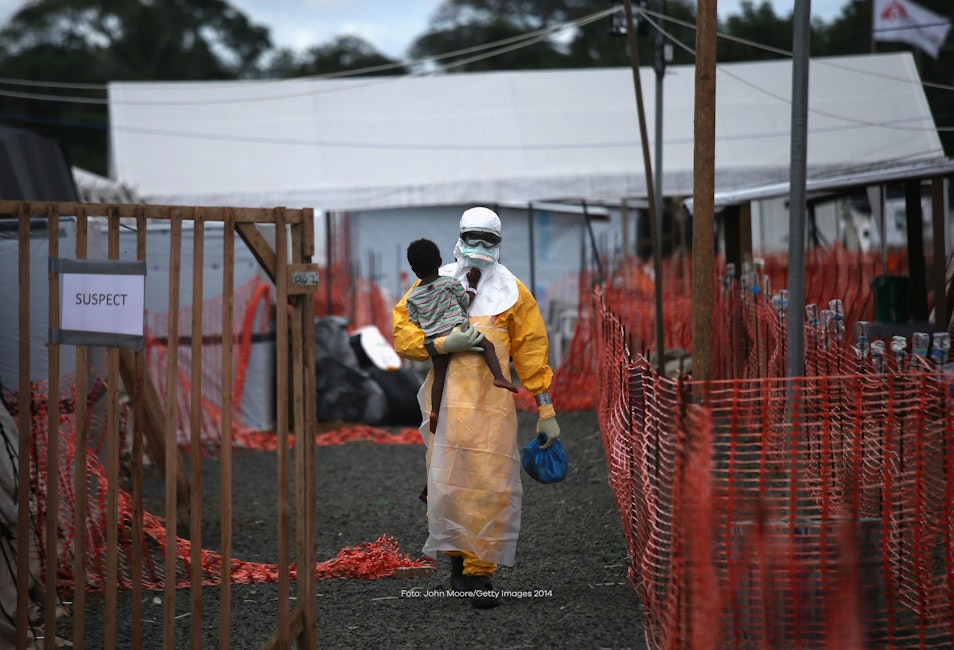 Een man draagt een kind tijdens een ebola uitbraak in Liberia.