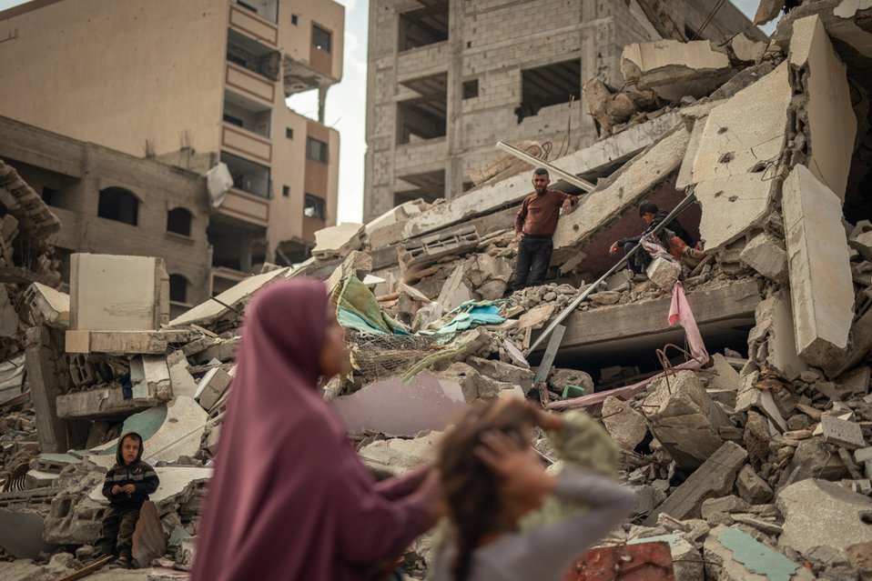 Een vrouw en haar kinderen zoeken naar hun spullen onder het puin in Gaza-Stad.