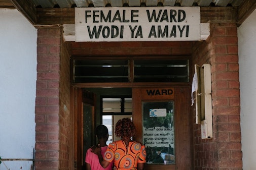 Rozi gaat samen met een patiënt een kliniek binnen in Malawi-MSF262529