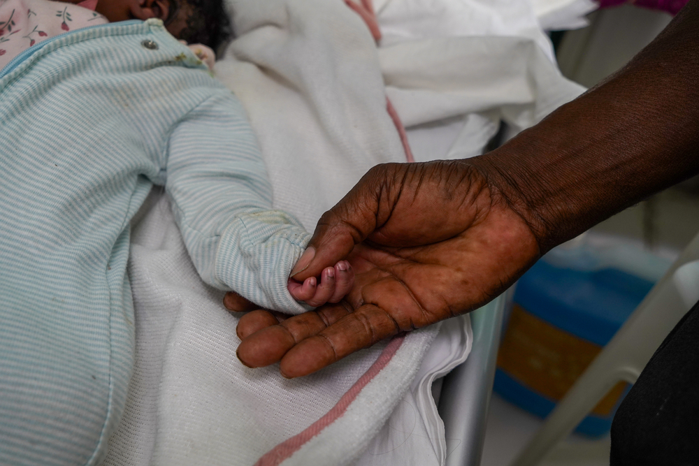 Hand van een pasgeboren baby in de hand van de grootvader.