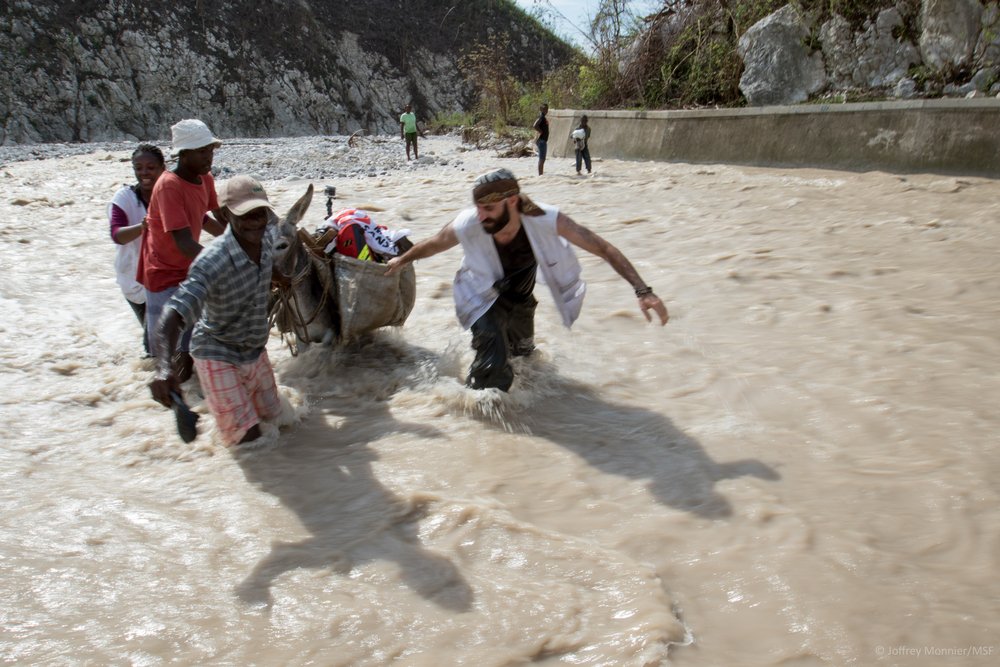 Na een orkaan Haïti heeft getroffen zijn veel gebieden overstroomd. Om toch hulp te bieden steken hulpverleners Adrien en Casssandre de rivier over.
