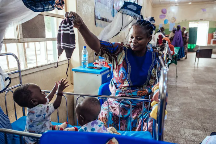 Amaka (35) speelt met haar twee zoons in een ziekenhuis in Sokoto, Nigeria