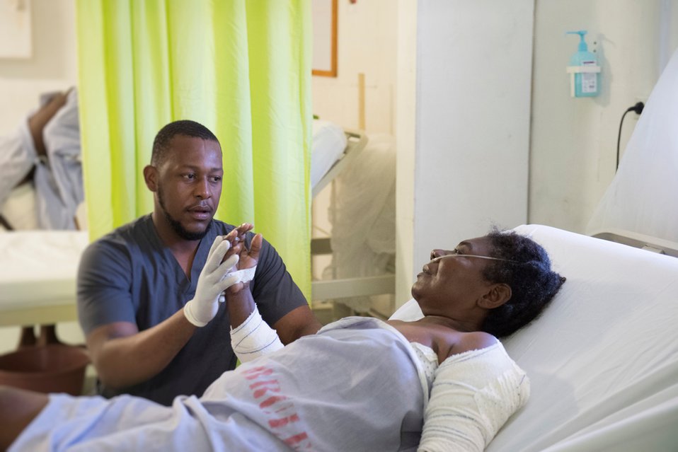 Een medewerker van Artsen zonder Grenzen doet fysiotherapeutische oefeningen met een patiënt in Haïti.