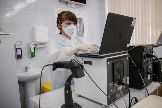 Een laborant in Minsk, Wit-Rusland, bij een moleculair testmachine die belangrijk is voor de behandeling van resistente tuberculose