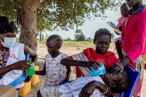Een moeder geeft haar kind medicatie als preventie tegen malaria