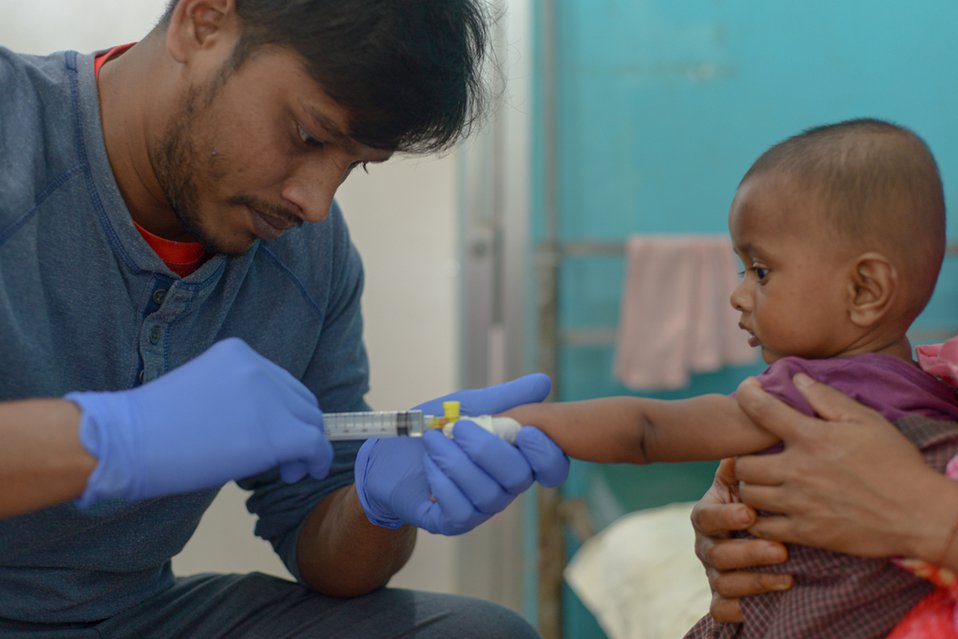 Een medewerker van Artsen zonder Grenzen vaccineert een baby in Bangladesh.