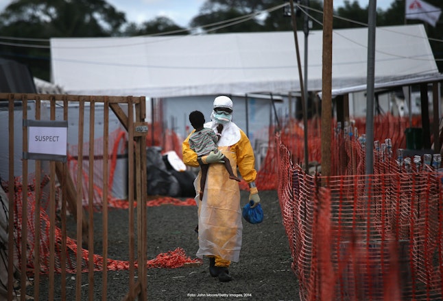 Een man draagt een kind tijdens een ebola uitbraak in Liberia.