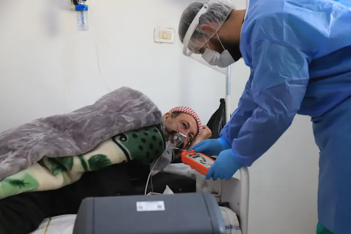 Verpleegkundige controleert het zuurstofniveau van een patiënt . Hij ligt op de COVID-19 afdeling in het ziekenhuis in Idlib, Syrië