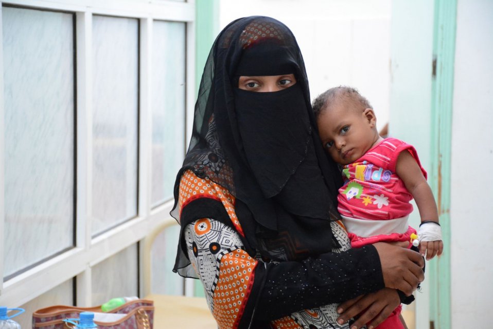 Een moeder draagt haar kind, dat cholera heeft, in het Al-Sadaqa ziekenhuis. Jemen, 2017
