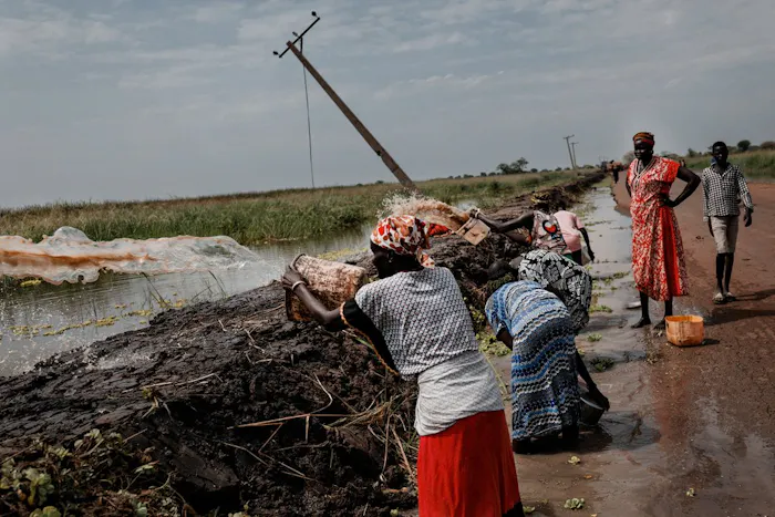 Vrouwen scheppen water en gooien dat over de dijk. © Sean Sutton