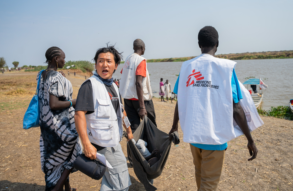 hulpverleners dragen kind naar boot
