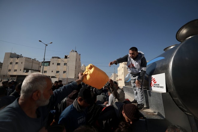 Een medewerker van Artsen zonder Grenzen deelt water uit in Rafah in Gaza.