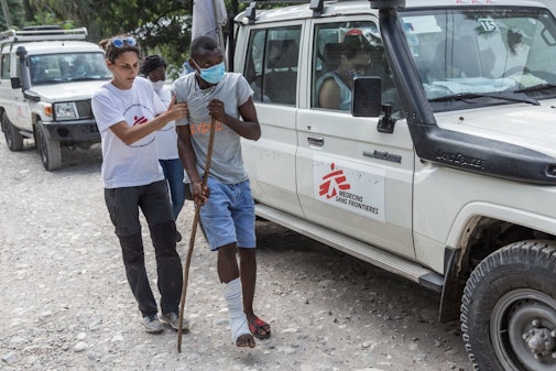 Na de aardbeving in Haïti helpt verpleegkundige Alessia deze patiënt richting onze mobiele kliniek