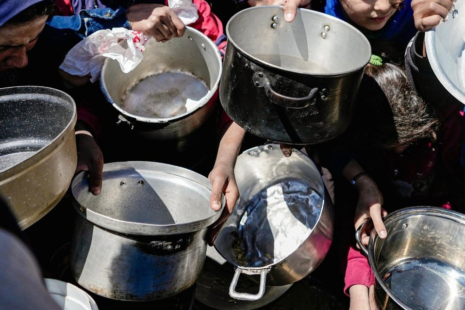 Kinderen staan met lege potten bij een gaarkeuken in Noord-Gaza.
