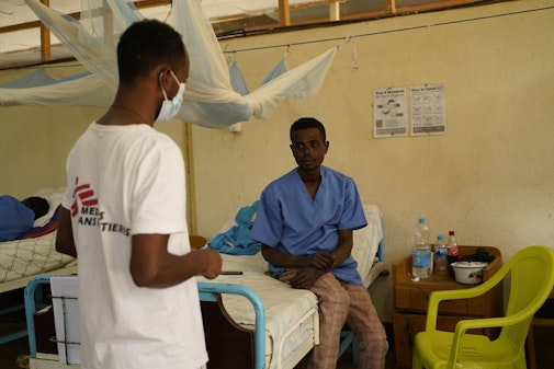 Een medewerker van Artsen zonder Grenzen met een patiënt in een ziekenhuis.