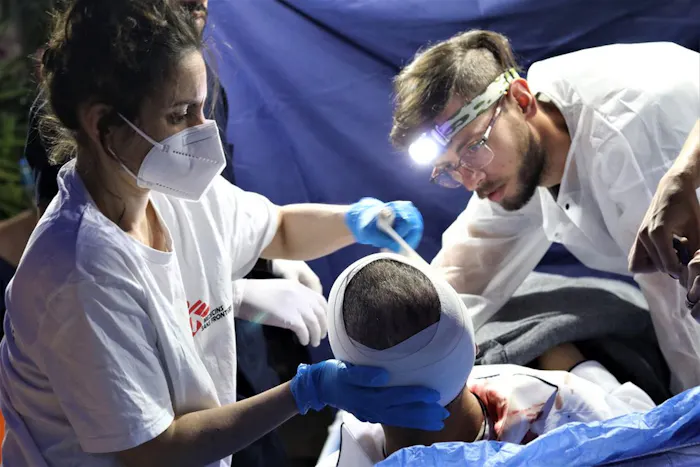 Twee medewerkers van Artsen zonder Grenzen onderzoeken een patiënt met een hoofdwond in Gaza.