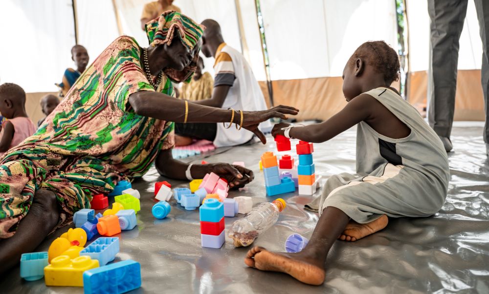 Een grootmoeder speelt met haar kleindochter in een tent speciaal ingericht voor speltherapie.