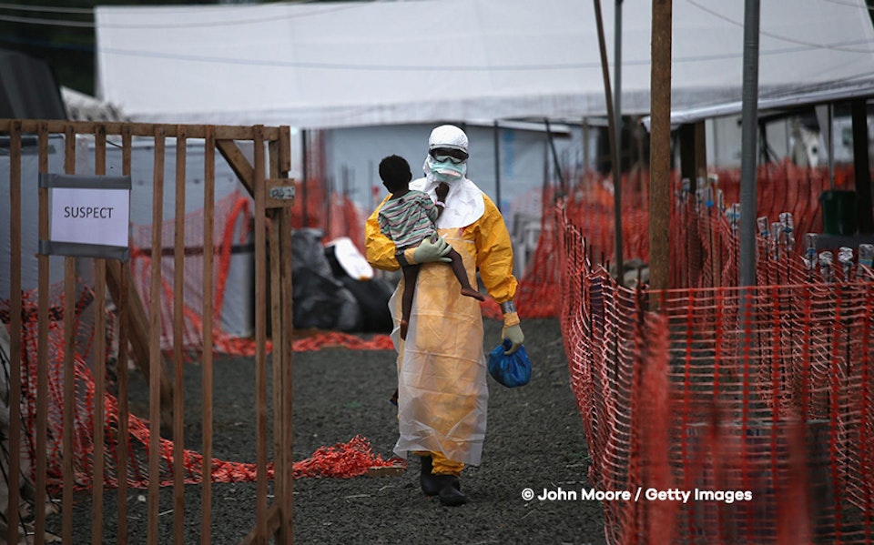Een man draagt een kind tijdens een ebola uitbraak in Liberia.