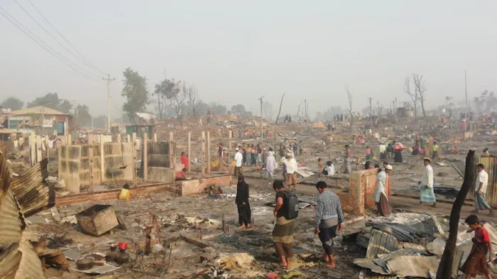 Mensen bij hun verwoeste hutten na de brand in het vluchtelingenkamp in Bangladesh