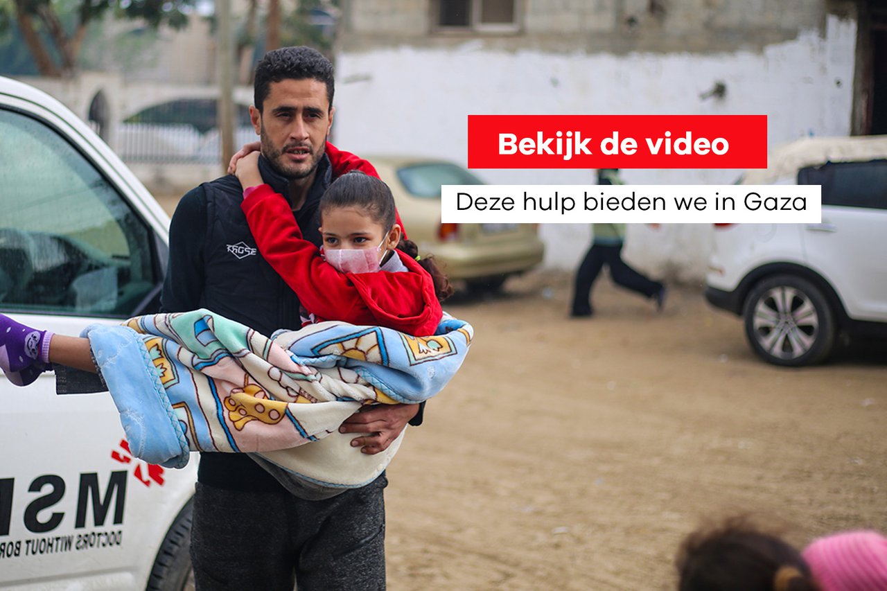 Een man draagt een gewond kind in Gaza.